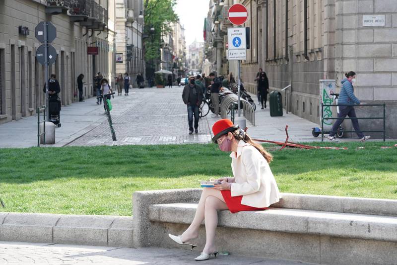 A woman wearing a protective face mask reads a book in Carignano square, Turin, Italy. EPA