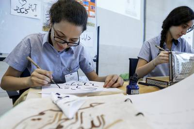 Dubai International Academy pupils Zain Shangiti, left, and Leila Gemei practise Arabic calligraphy at the KHDA conference held at the Mohammed bin Rashid Academic Medical Academy. Antonie Robertson / The National