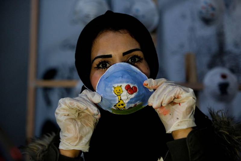 Palestinian artist Samah Said puts on a painted dust mask for a project raising awareness about the COVID-19 coronavirus pandemic, in Gaza City.   AFP