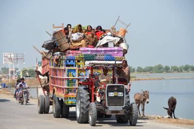 Displaced flood-affected families travel on a tractor trailer with their belongings near a makeshift camp at Dera Allah Yar in Jaffarabad. AFP