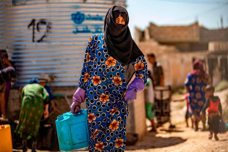 A displaced Syrian brings water back to their camp in a camp for the displaced in Syria's northeastern city of Hasakah on August 24, 2020.  / AFP / Delil SOULEIMAN
