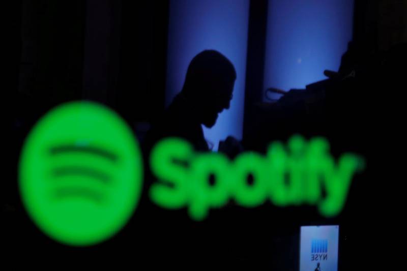 FILE PHOTO: A trader is reflected in a computer screen displaying the Spotify brand before the company begins selling as a direct listing on the floor of the New York Stock Exchange in New York, U.S., April 3, 2018.  REUTERS/Lucas Jackson/File Photo                        GLOBAL BUSINESS WEEK AHEAD