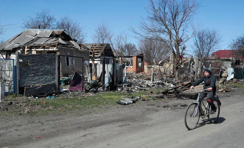 A boy rides a bicycle past a house that was damaged by shelling in Andriivka village, not far from Kyiv. EPA