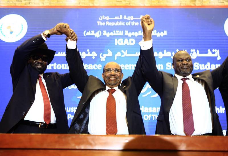 Sudanese President Omar al-Bashir (C) raises held hands with South Sudan's President Salva Kiir Mayardit (L) and South Sudanese rebel leader Riek Machar (R) after the two South Sudanese arch-foes agreed in Khartoum on June 27, 2018, to a "permanent" ceasefire to take effect within 72 hours in their country. The agreement called "Khartoum Declaration" is part of a peace bid launched by East African leaders to end the devastating war in South Sudan since December 2013 which has killed tens of thousands and left displaced about four million. / AFP / ASHRAF SHAZLY
