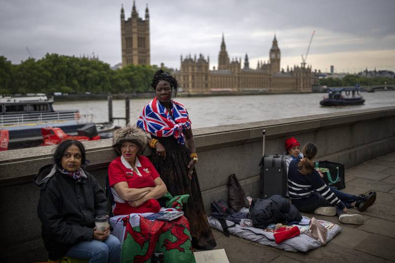 Vanessa, Anne and Grace, from left to right, wait opposite the Palace of Westminster to be first in line bidding farewell to Queen Elizabeth in London. AP