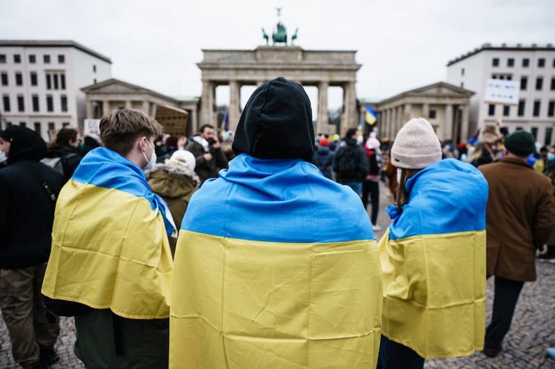 People wear the Ukrainian national flag during a protest in front of the Brandenburg Gate in Berlin. EPA