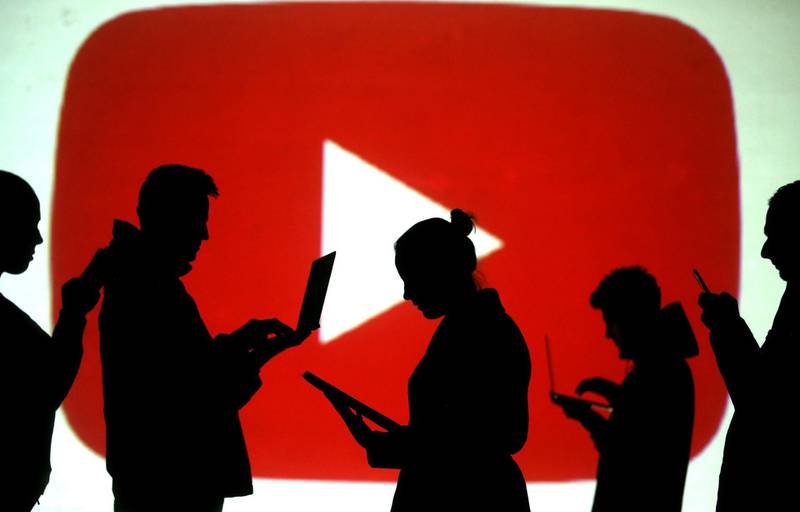 FILE PHOTO: Silhouettes of laptop and mobile device users are seen next to a screen projection of the YouTube logo in this picture illustration taken March 28, 2018.  REUTERS/Dado Ruvic/Illustration/File Photo