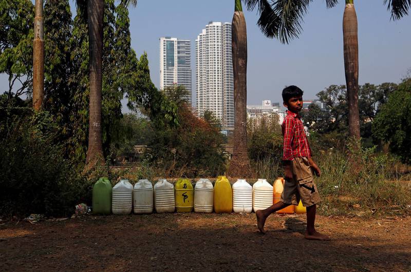 A boy walks past plastic containers filled with drinking water at a tribal settlement in Mumbai, India, March 29, 2018. REUTERS/Francis Mascarenhas