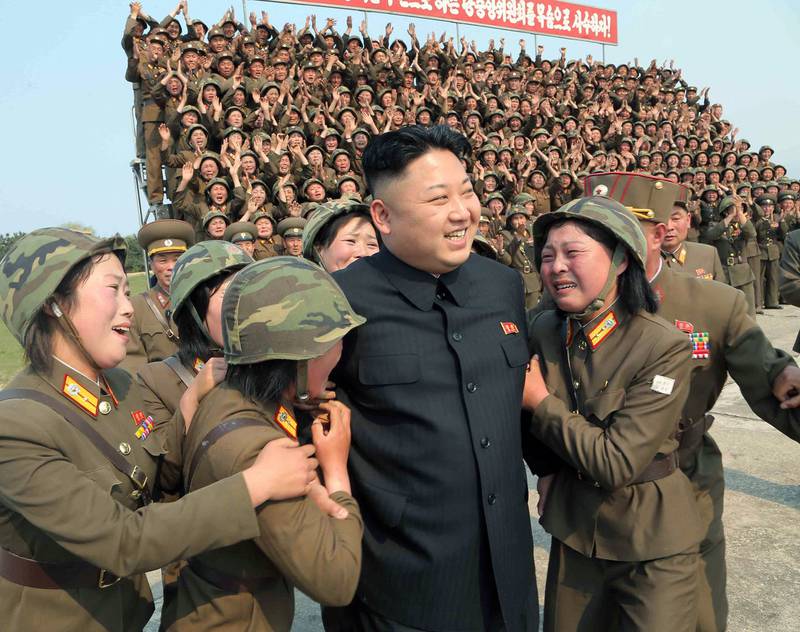 Kim Jong-un smiles with soldiers after inspecting the multiple-rocket launching drill of the women's sub-units under the Korean People's Army  Unit 851 at an undisclosed location in North Korea, April 2014. KCNA / AFP