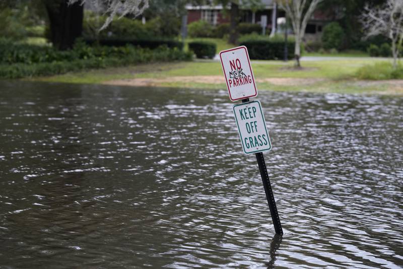 A sign warns against parking on the grass at Quarterman Park in north Charleston, where waters from Hurricane Ian covered a footpath around a pond as well as grassy areas and the root systems of Spanish moss-covered trees. AP