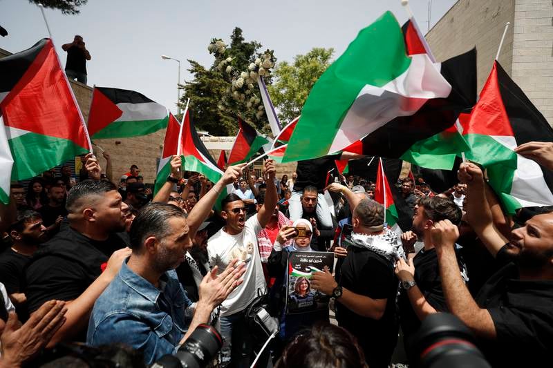 People wave Palestinian flags as they gather to pay tribute to  Abu Akleh before her funeral. EPA