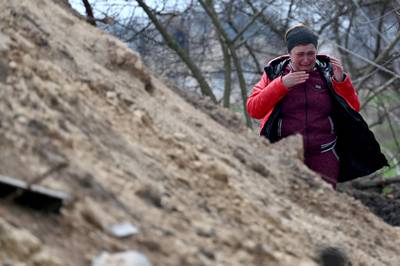 A relative cries after the body of a civilian was exhumed from a shallow grave near his home in the village of Andriivka, in Kyiv region. AFP