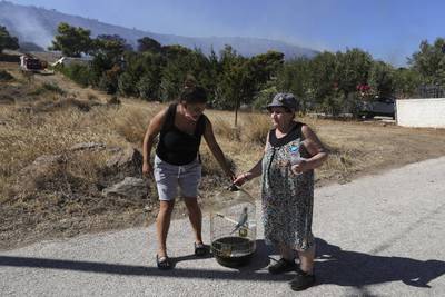 A family moves out of the fire zone with their parakeet after a forest fire broke out in Markati village of Keratea town near Athens, on August 16. Getty Images