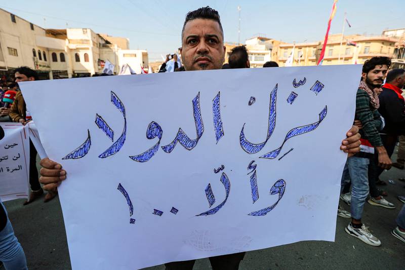 A man holds a sign reading in Arabic: 'Depreciate the rate of the [US] dollar, or else!' AFP