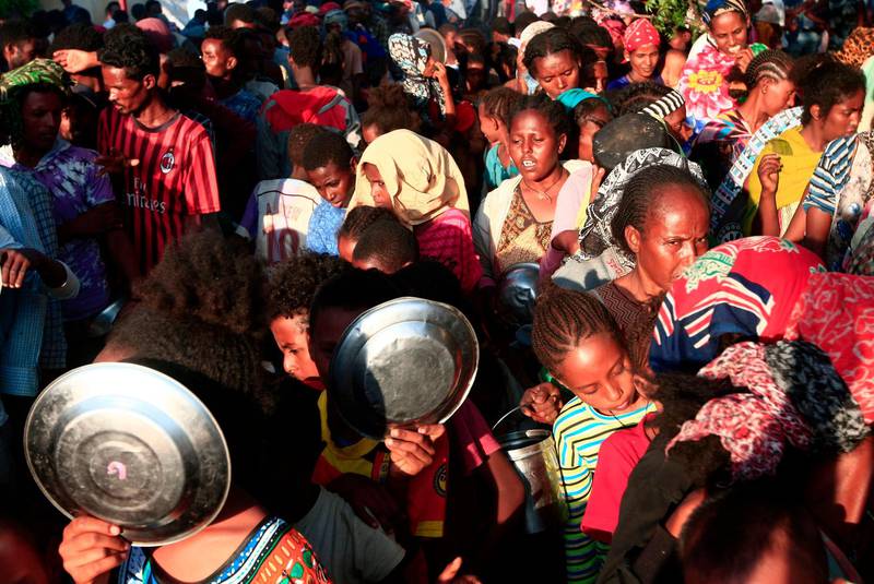Ethiopian migrants who fled intense fighting in their homeland of Tigray,  wait for their ration of food in the border reception center of Hamdiyet, in the eastern Sudanese state of Kasala.  AFP