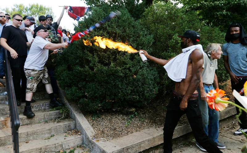 A counter demonstrator uses a lighted spray can against a white nationalist demonstrator at the entrance to Lee Park in Charlottesville. Steve Helber / AP/