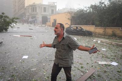 A resident stands in the street by a destroyed car, following the  explosion near by at the port of Beirut. Bloomberg