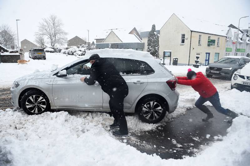 People push a car out of the snow in Auchterarder, central Scotland. AFP