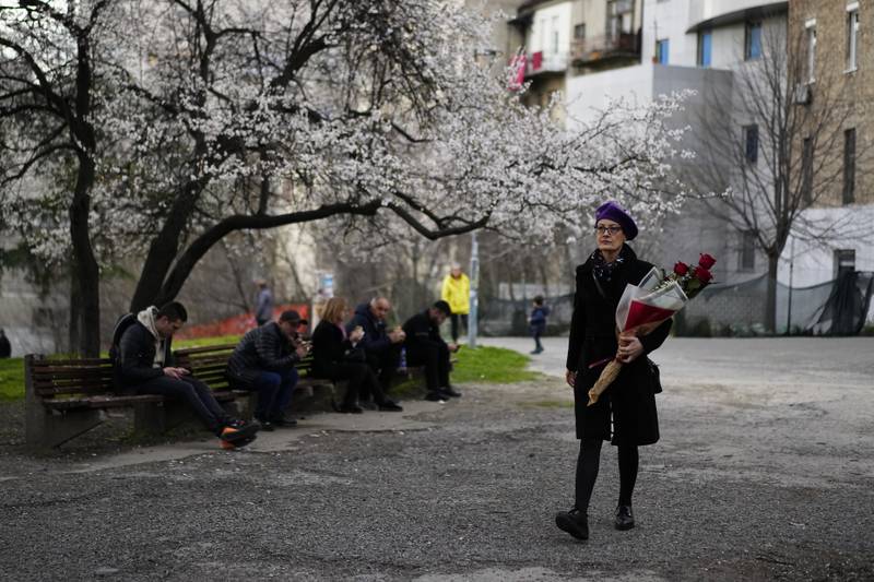 A woman holds a bouquet of flowers on a street in Belgrade, Serbia. AP