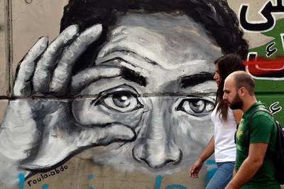 Protesters pass by a wall with graffiti during ongoing anti-government in Beirut, Lebanon.  EPA