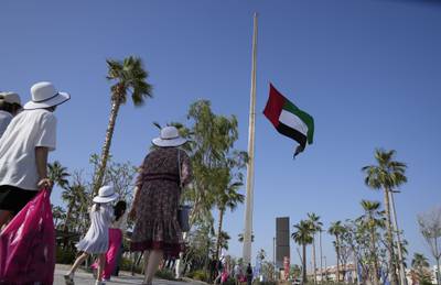 People pass by the UAE national flag, flying at half-staff, following the announcement of President Sheikh Khalifa's death. AP Photo