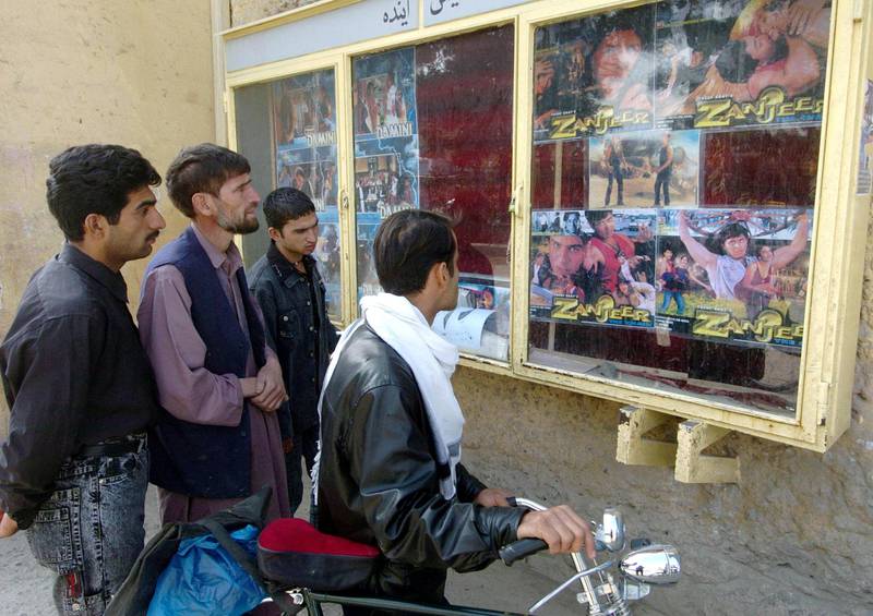 Afghan men look at film posters outside the Park Cinema in Kabul, 16 October 2005.  Following the invasion of US forces and the ouster of the Taliban in 2001, celebrated Afghan film director Siddaq Barmak was appointed to head the Afghan Film Institute and started making his own short films again, and reopened nine theatres in Kabul using the latest digital technology that now show mostly Bollywood flicks.    AFP PHOTO/SHAH Marai (Photo by SHAH MARAI / AFP)