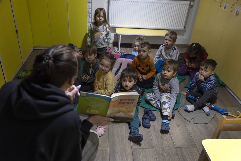 Julia Palovskaya reads to children during an air raid drill in the basement shelter at a preschool in Lviv, April 2022. Getty Images
