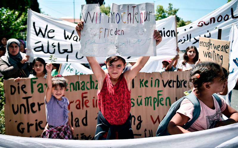 TOPSHOT - A boy holds up a placard reading in German 'We only want peace' as refugees, mainly coming from Syria, protest outside the German embassy in Athens on July 19, 2017 against delays in the  reunification process with their families in Germany.
The German government has significantly cut back on family reunions for refugees arriving from Greece since May 2017. Asylum seekers - mostly Syrian refugees in Greece's case - are entitled to join family members elsewhere in the European Union within six months from the date their request is approved.  / AFP PHOTO / LOUISA GOULIAMAKI