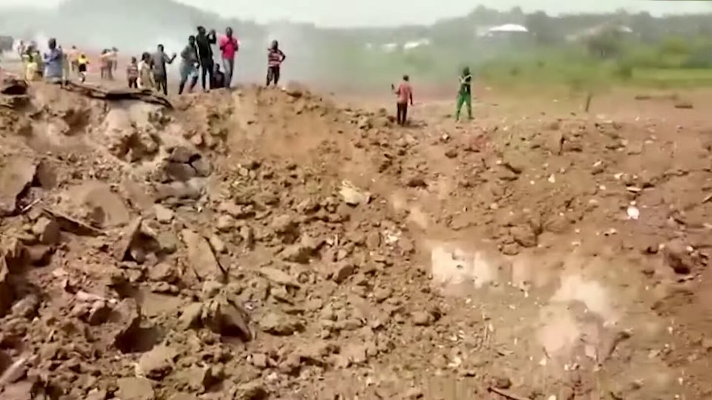 Blast survivors look at a crater left when a lorry-load of explosives detonated. Photo: Screenshot from video