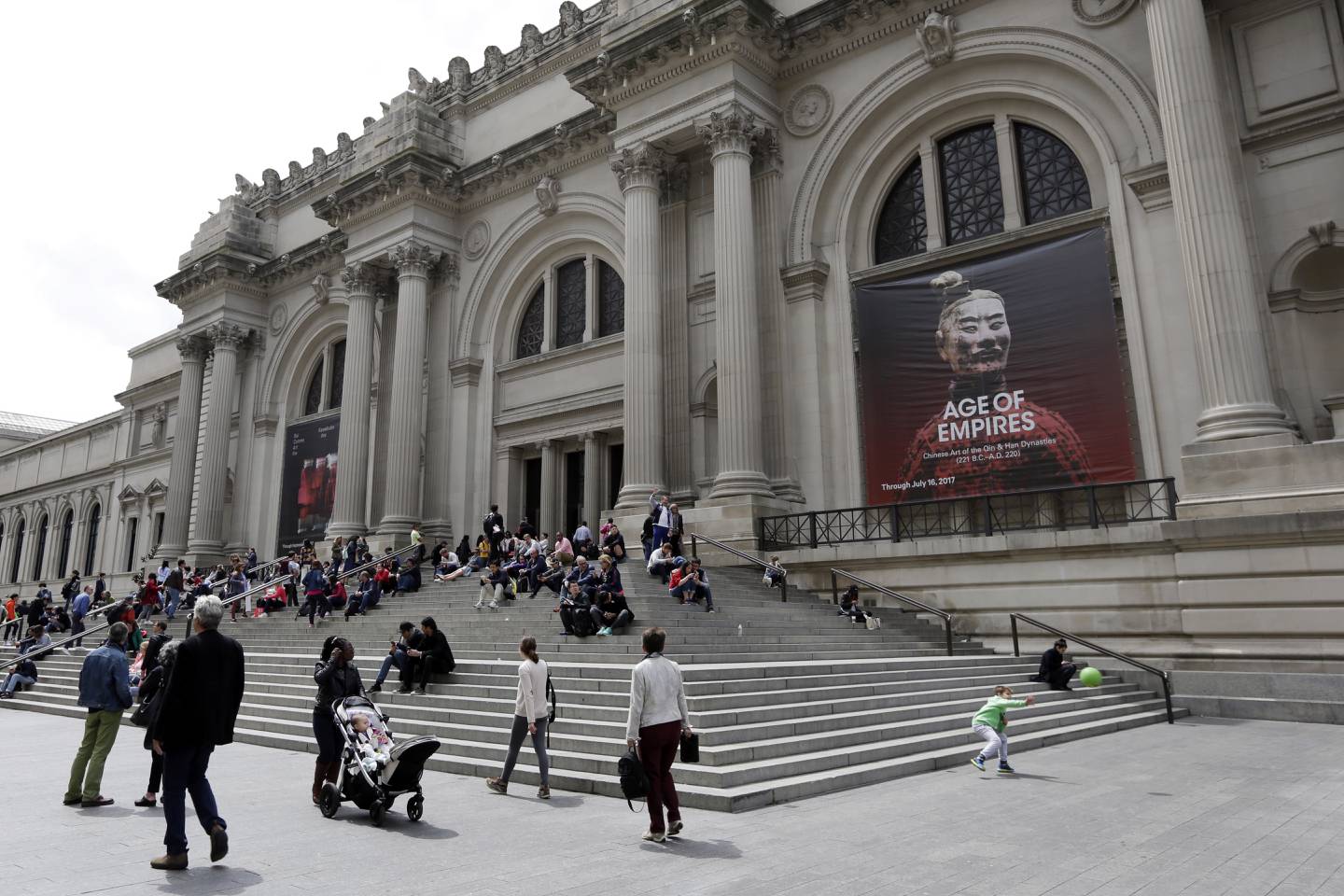 In this May 10, 2017 photo, people sit on the steps at the Fifth Avenue entrance to the Metropolitan Museum of Art in New York. The museum is rebounding from more than a year of internal turmoil and financial problems. As part of its recovery efforts, the museum is considering a mandatory admissions fee for visitors from outside New York state. (AP Photo/Richard Drew)