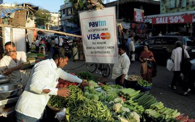 A sign advertising Indian electronic and cellpohne-based payment system PAYTM hangs at a roadside vegetable stall in Mumbai on February 25, 2017.  / AFP PHOTO / PUNIT PARANJPE