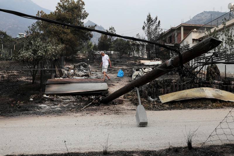 A man collects belongings after a forest fire in Kineta village, west of Athens. AP Photo