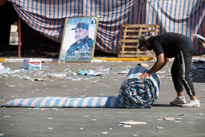 A supporter of Mr Al Sadr rolls up a mattress as their encampment in the Green Zone is dismantled. AFP