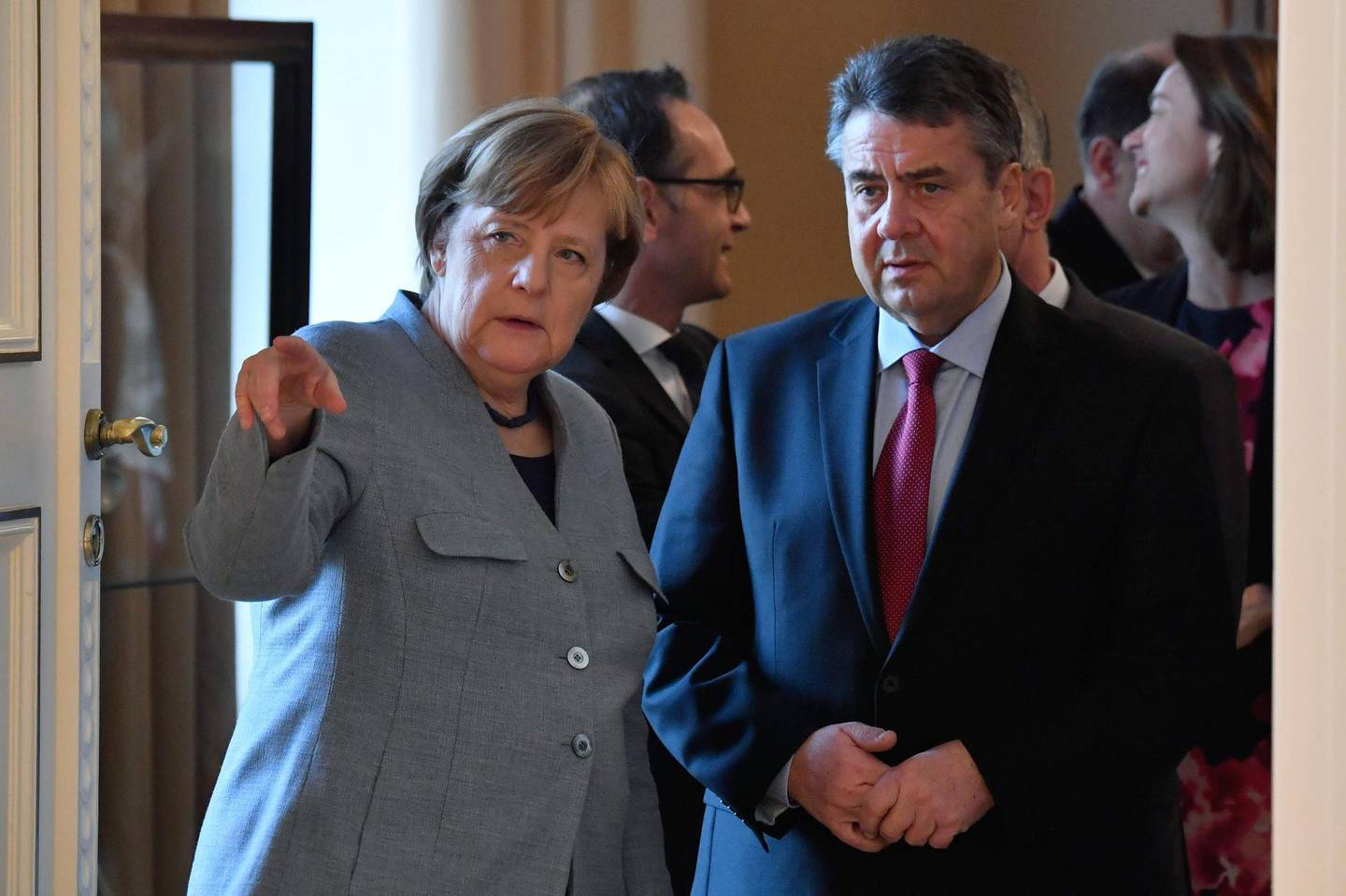 German Vice Chancellor and Foreign Minister Sigmar Gabriel (R) and German Chancellor Angela Merkel talk as they wait to be introduced to the German President during a New Year's reception at the presidential Bellevue Palace in Berlin on January 9, 2018. / AFP PHOTO / John MACDOUGALL