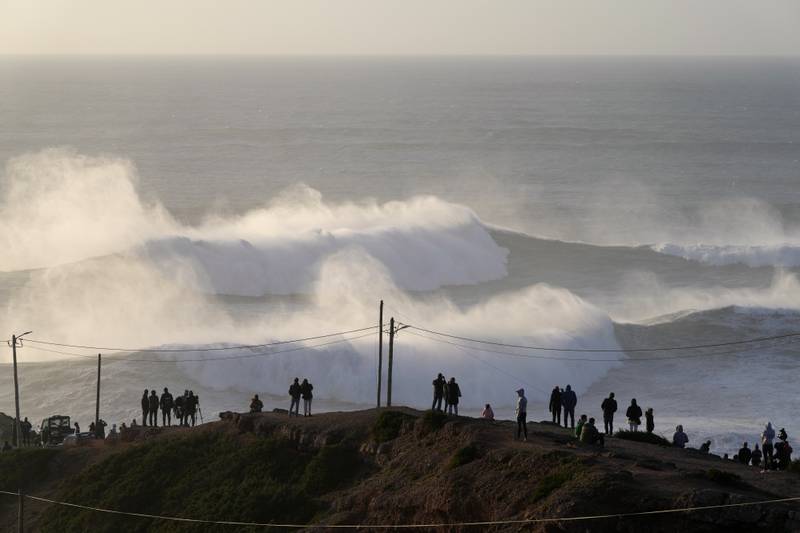 People stand on the top of cliffs to watch a surfing session at Praia do Norte, or North Beach, in Nazare, Portugal. AP