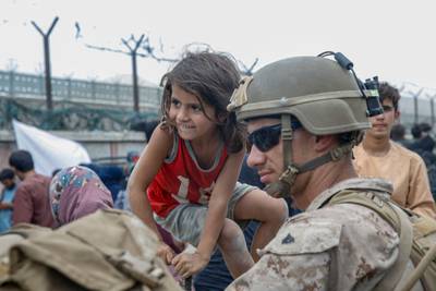 A US Marine waits with a child at the airport in Kabul. AFP