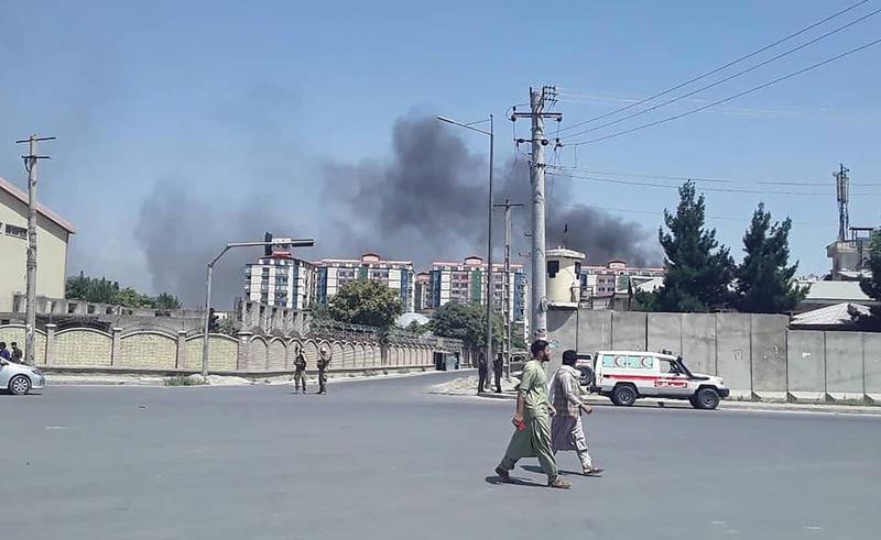 Afghan men walk on a road as smoke rises from the site of an attack in Kabul.  AFP