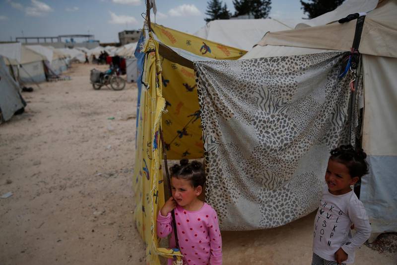 Members of the extended Syrian family of Sweidan, from Douma, who fled after enduring weeks of bombing, near-starvation from a crippling siege and a suspected chemical attack, stand outside the family tent in a camp for internally displaced people in al-Bab, northern Syria, Tuesday, May 29, 2018. The family is crammed into a single tent in a squalid and overcrowded camp for those who fled the fighting near the capital of Damascus. But the Sweidan family had no choice except to leave their hometown and they are now resigned to a life of exile in northern Syria. (AP Photo/Lefteris Pitarakis)
