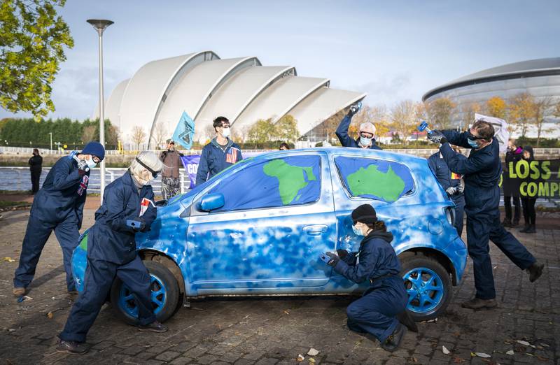 Activists from Extinction Rebellion take part in a 'Loss and Damage' protest performance, where a car painted to look like a globe was smashed outside the Cop26 summit in Glasgow. PA