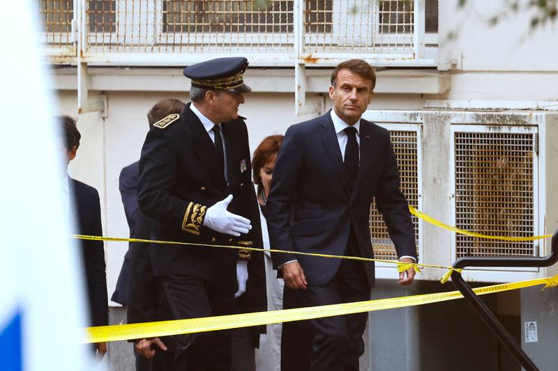 President Emmanuel Macron, right, arrives at the school in north-eastern France where a teacher was killed by an extremist. AFP