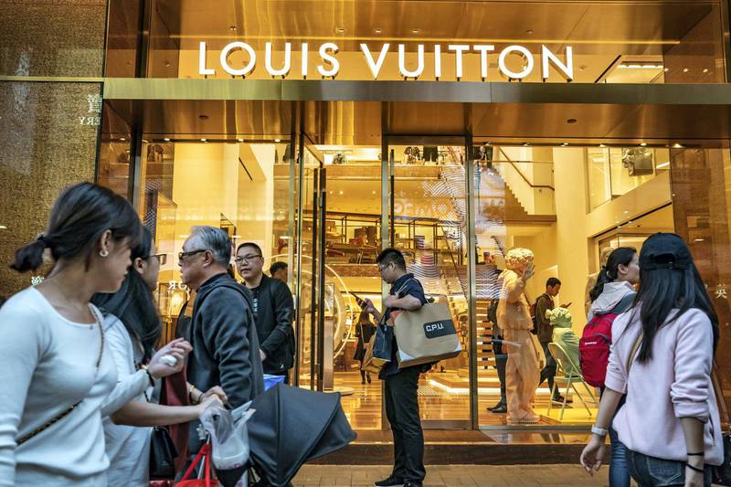 Pedestrians walk past a Louis Vuitton store, operated by LVMH Moet Hennessy Louis Vuitton SE, on Canton Road in the Tsim Sha Tsui district of Hong Kong, China, on Sunday, Feb. 3, 2019. The week-long Lunar New Year holiday, starting Feb. 4, will provide the next litmus test of the resilience of the Chinese shopper. The seven-day period sees hundreds of millions of people travel within the country to see relatives, fly overseas to takevacations - and open their wallets to buy gifts. Photographer: Anthony Kwan/Bloomberg