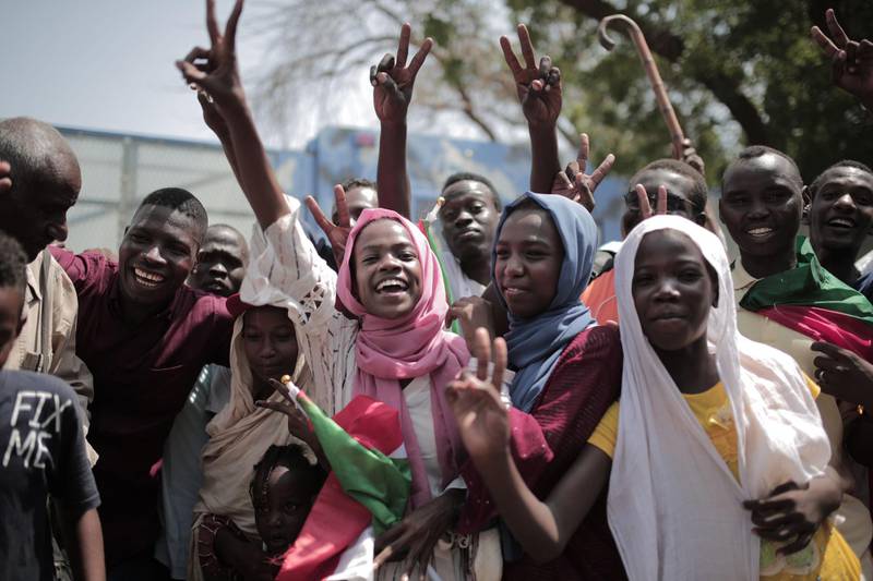 Sudanese men and women celebrate outside the Friendship Hall in the capital Khartoum where generals and protest leaders signed a historic transitional constitution meant to pave the way for civilian rule in Sudan.  AFP