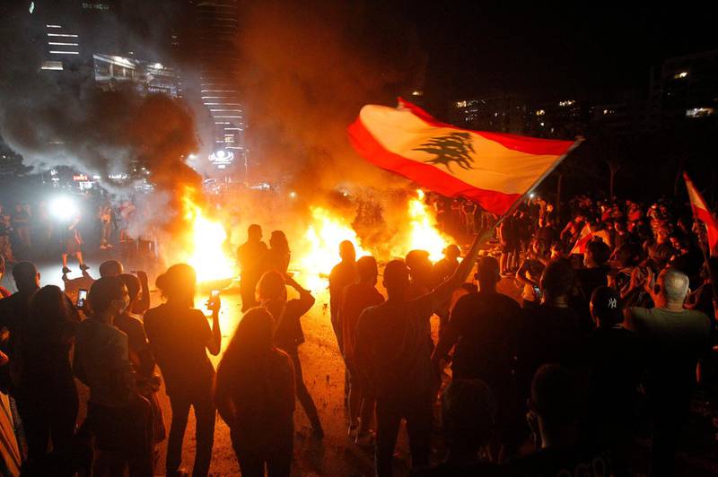 Anti-government protesters carry Lebanese flags and burn tyres as they block the main highway in north of Beirut during a protest over deteriorating living conditions. EPA