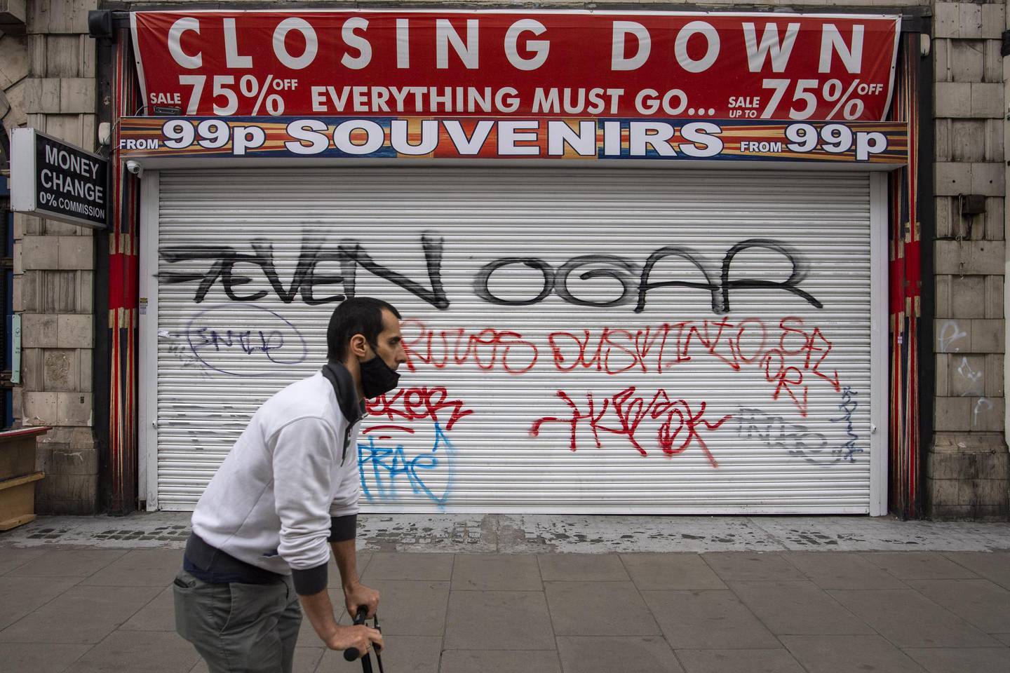 LONDON, UNITED KINGDOM - JUNE 12: A man in a face mask rides a scooter past a shuttered shop on Oxford Street on June 12, 2020 in London, England.  As the British government further relaxes Covid-19 lockdown measures in England, this week sees preparations being made to open non-essential stores and Transport for London handing out face masks to commuters. International travelers arriving in the UK will face a 14-day quarantine period. (Photo by Justin Setterfield/Getty Images)