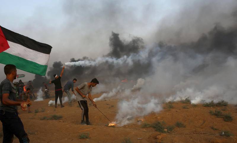 Protesters try to throw back tear gas canisters fired by Israeli troops near the fence of the Gaza Strip border with Israel, during a protest east of Gaza City. AP Photo