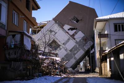 A man walks near a damaged building that leans on a neighbouring house in Golbasi, Turkey. AP