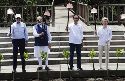 From left, Mr Biden, Mr Modi, Mr Widodo and Ms von der Leyen hold up their shovels during the mangrove planting. AP