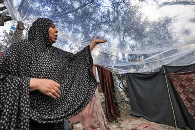 A Palestinian woman stands under a plastic sheet spread to shelter from the rain. AFP