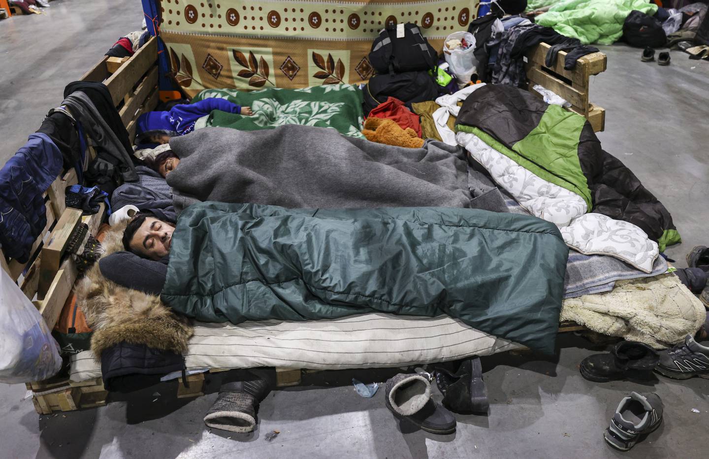 A family sleeps at the transport and logistics center near the Bruzgi checkpoint at the Belarusian-Polish border, in the Grodno region, Belarus, 24 November 2021.  Asylum-seekers, refugees and migrants from the Middle East arrived at the Belarusian-Polish checkpoint of Bruzgi-Kuznica aiming to cross the border.  Thousands of people who want to obtain asylum in the European Union have been trapped at low temperatures at the border since 08 November.   EPA / STRINGER