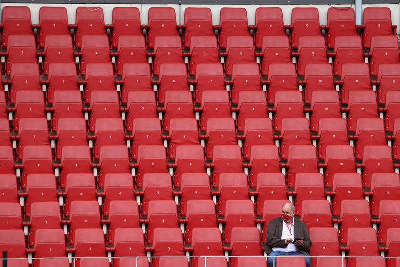 A man wearing a face mask sits in the stands before the match. Reuters